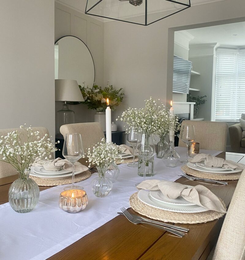 Dorset dining table styled with white table runner, white crockery and white flowers in small vases.