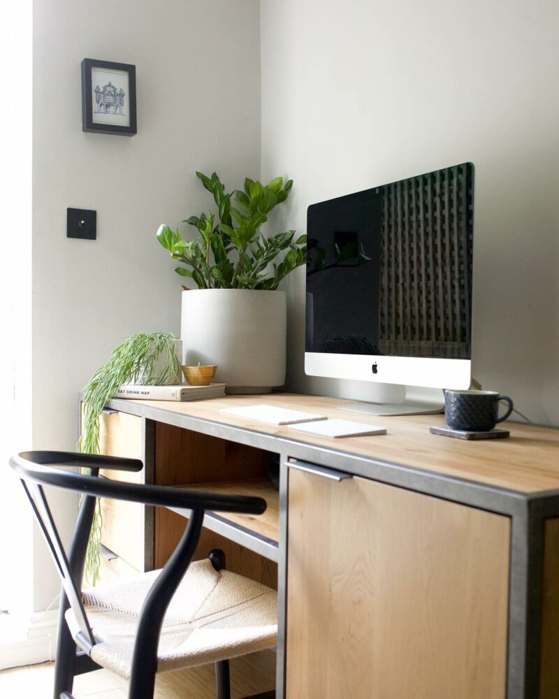 Brooklyn oak and metal desk in a home office with plants and a computer.