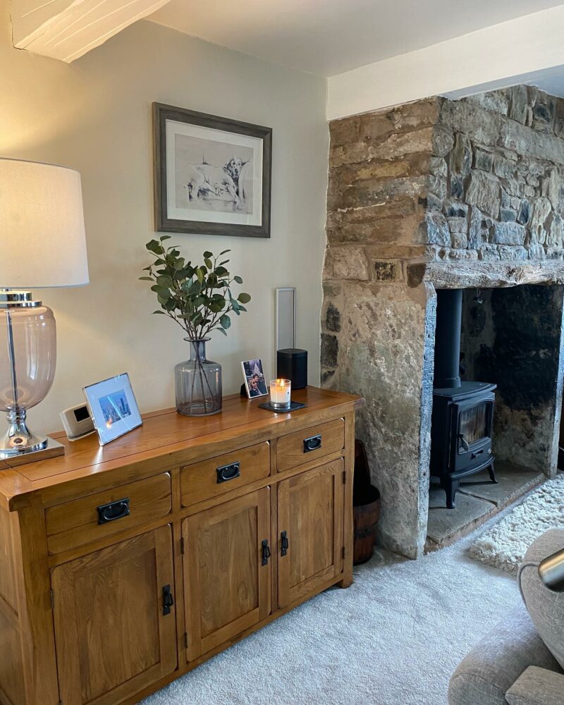 Oak Furnitureland Original Rustic traditional sideboard in an alcove next to a country cottage stone fireplace.