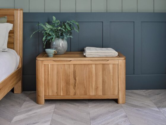 Natural oak Romsey blanket box in a bedroom with blue panelling.
