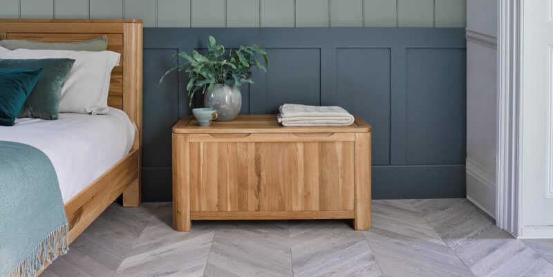 Natural oak Romsey blanket box in a bedroom with blue panelling.