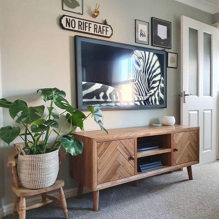 Parquet TV unit in a living room with an art TV placed above and houseplants to the side.