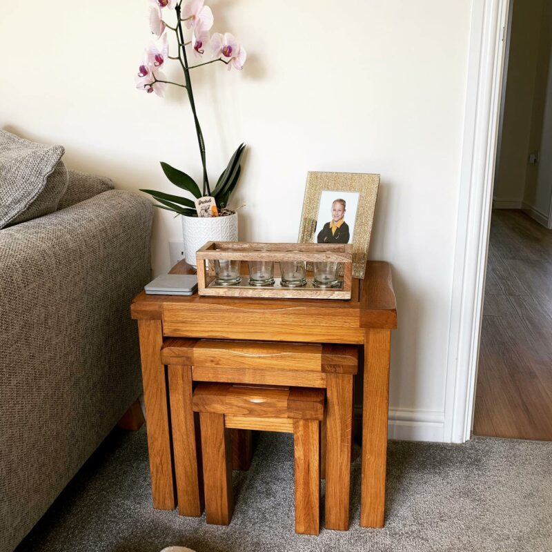 Living room with a nest of three Original Rustic tables topped with a photo frame, orchid and candles.