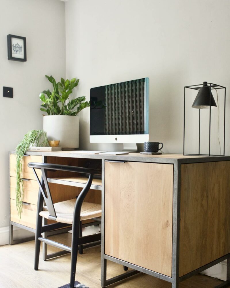 Brooklyn desk in a home office with plants, computer and industrial-style lighting. 