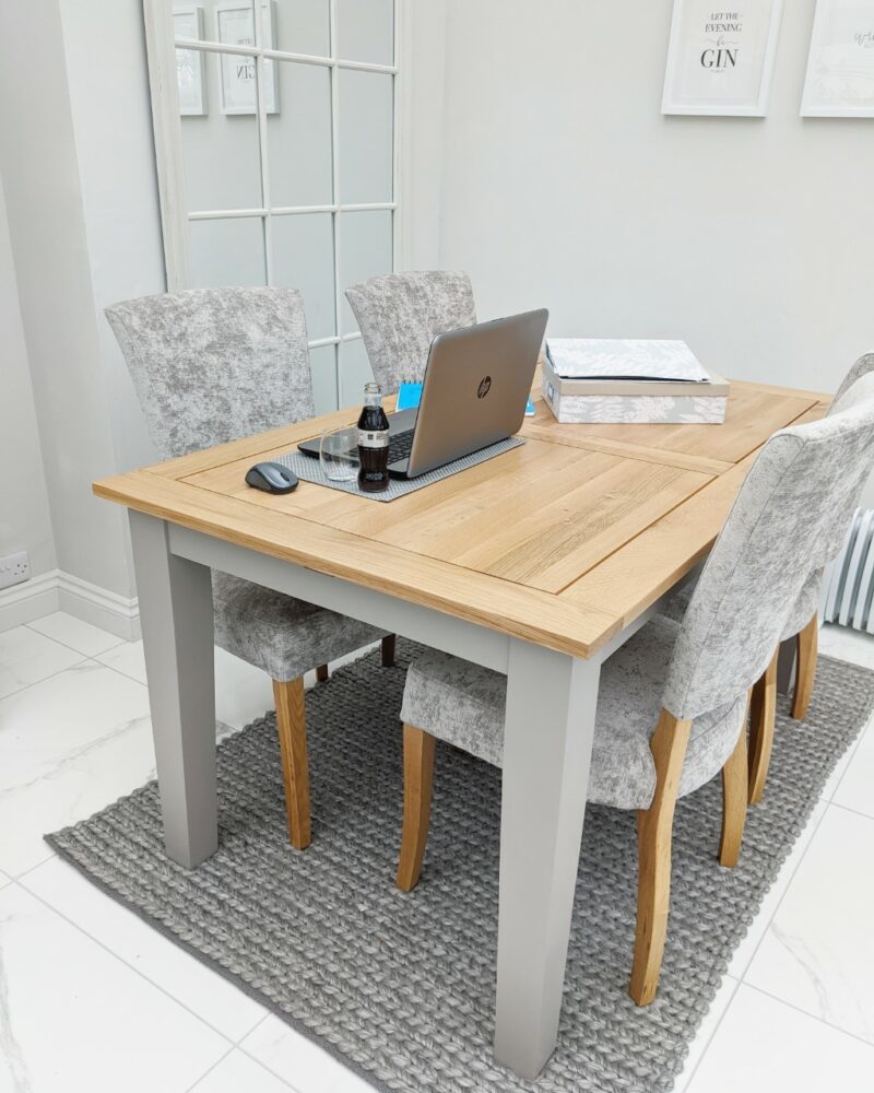 St. Ives grey and natural oak dining table and grey velvet chairs set up ready for home working with a laptop.