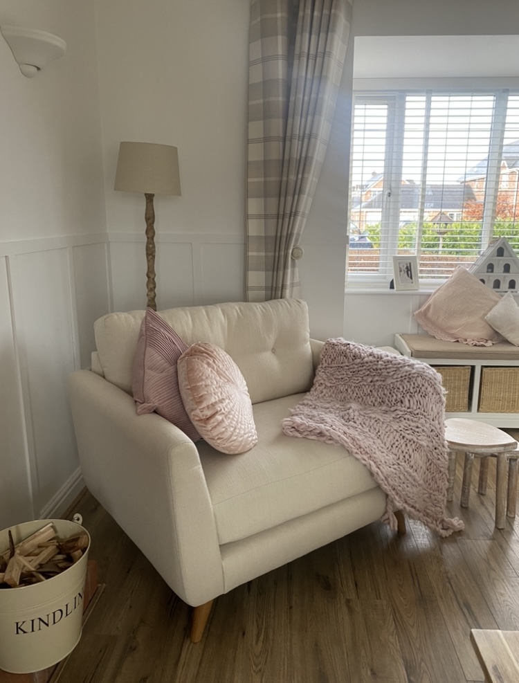 Cream Oak Furnitureland Evie loveseat styled with pale pink accessories.