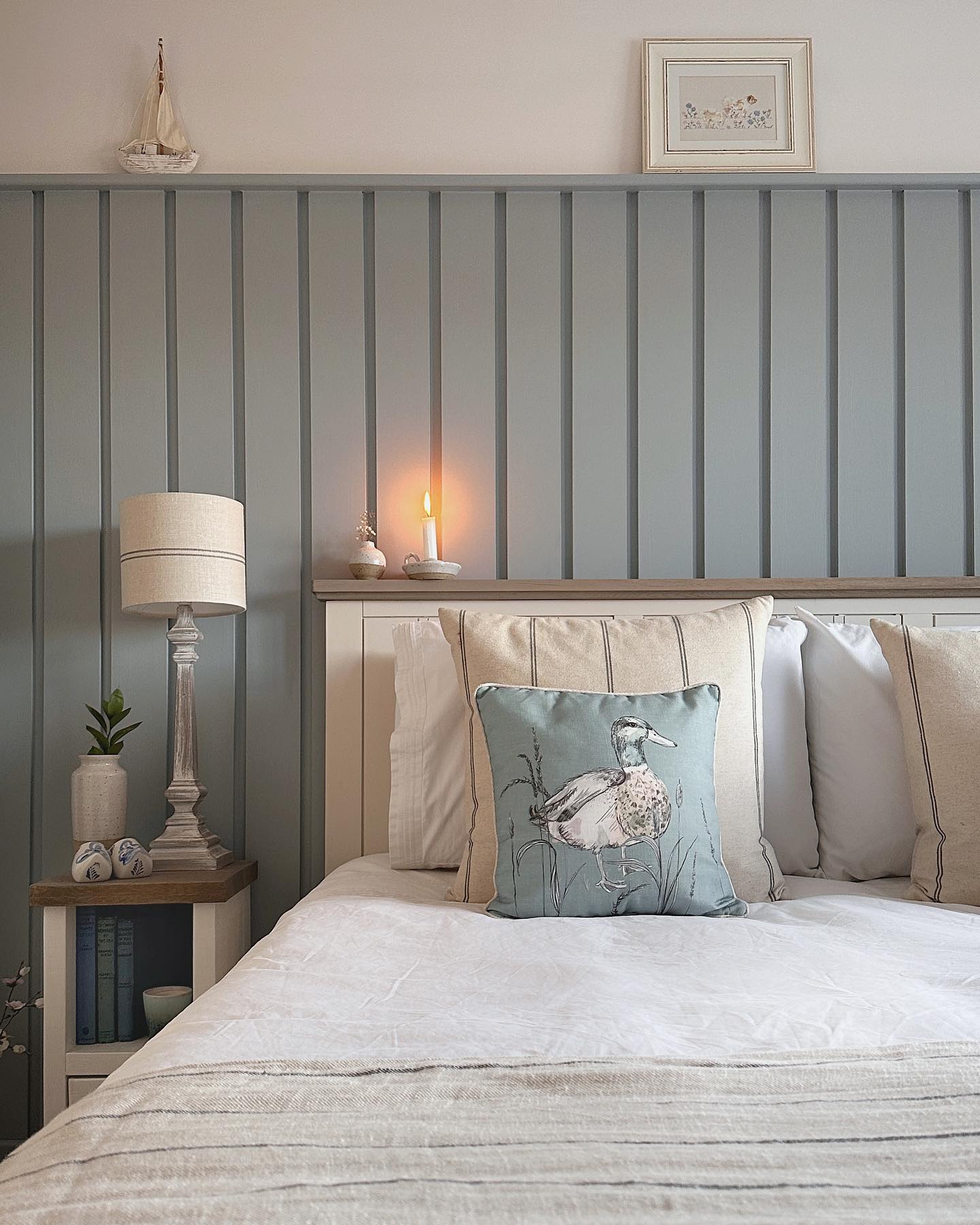 Coastal-inspired bedroom with duck egg blue wall panelling in a peaceful scheme.