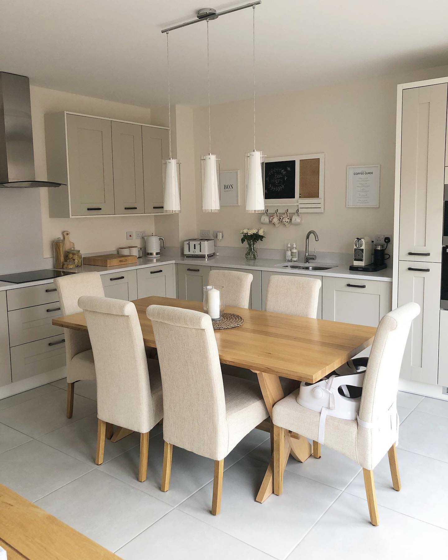 Neutral kitchen with Oak Furnitureland dining table and cream upholstered scroll back chairs.