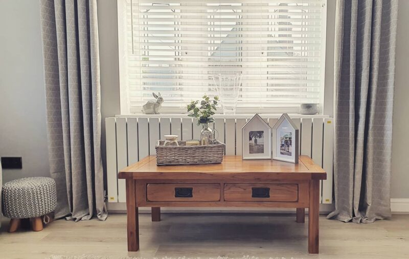 Original Rustic coffee table next to a radiator in a contemporary home with grey curtains and accessories. 