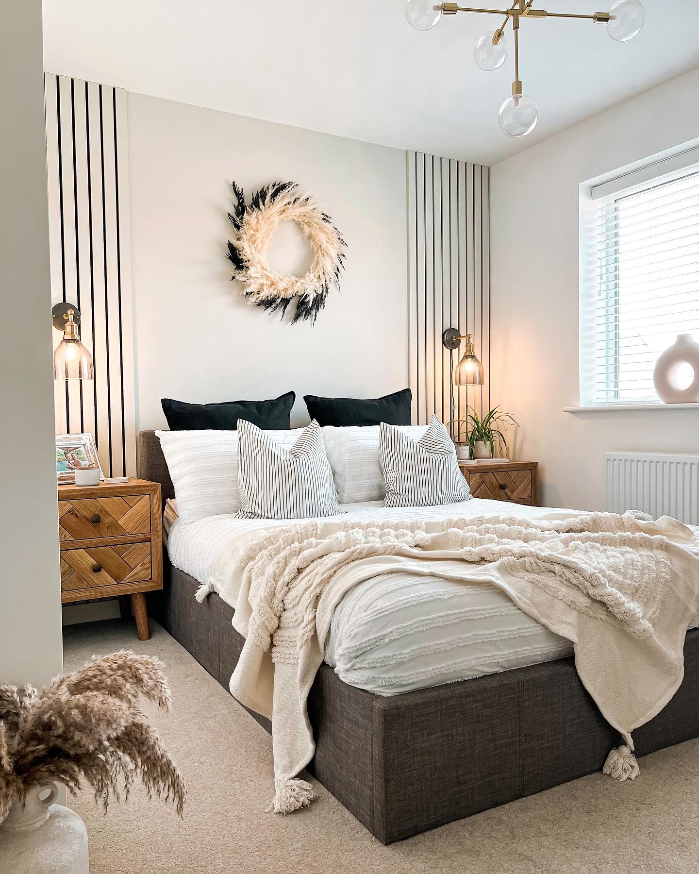 Glazed oak Parquet bedside tables in a bedroom filled with texture, including throws, cushions, dried flowers and decorative objects.