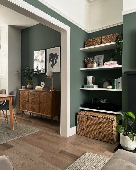 Living room/diner with walls painted in sage green and natural oak furniture.