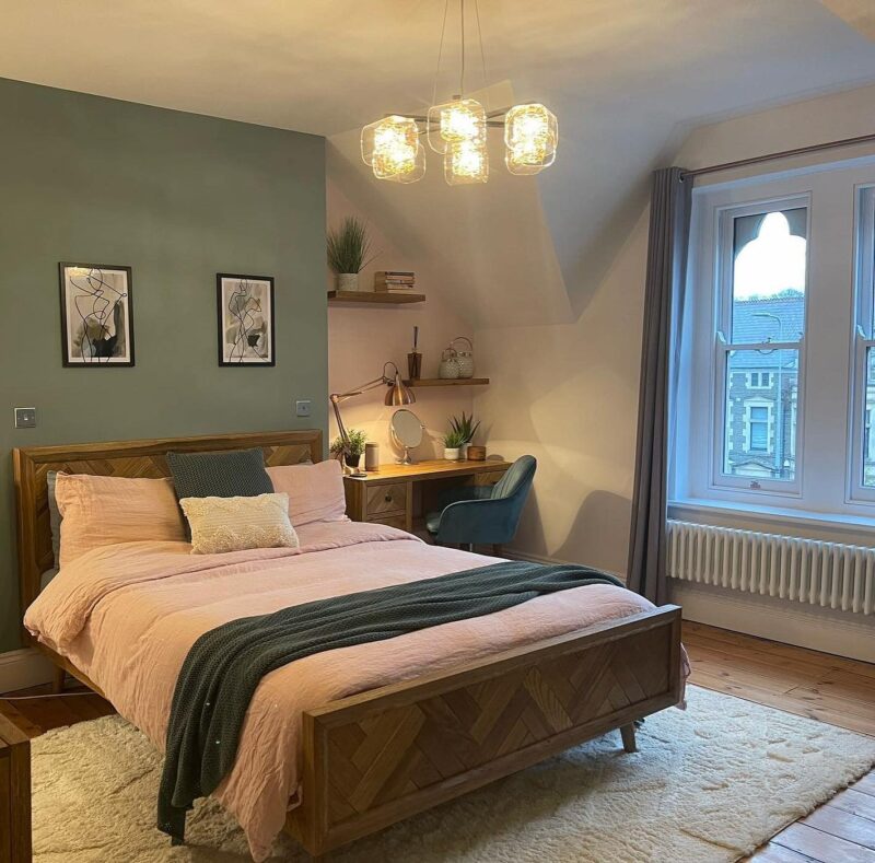Parquet natural oak bed in a room decorated with green walls and finished with pink bedding and green accents.