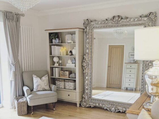 Oak Furnitureland cream painted Shay bookcase in luxe room with large silver statement wall mirror.