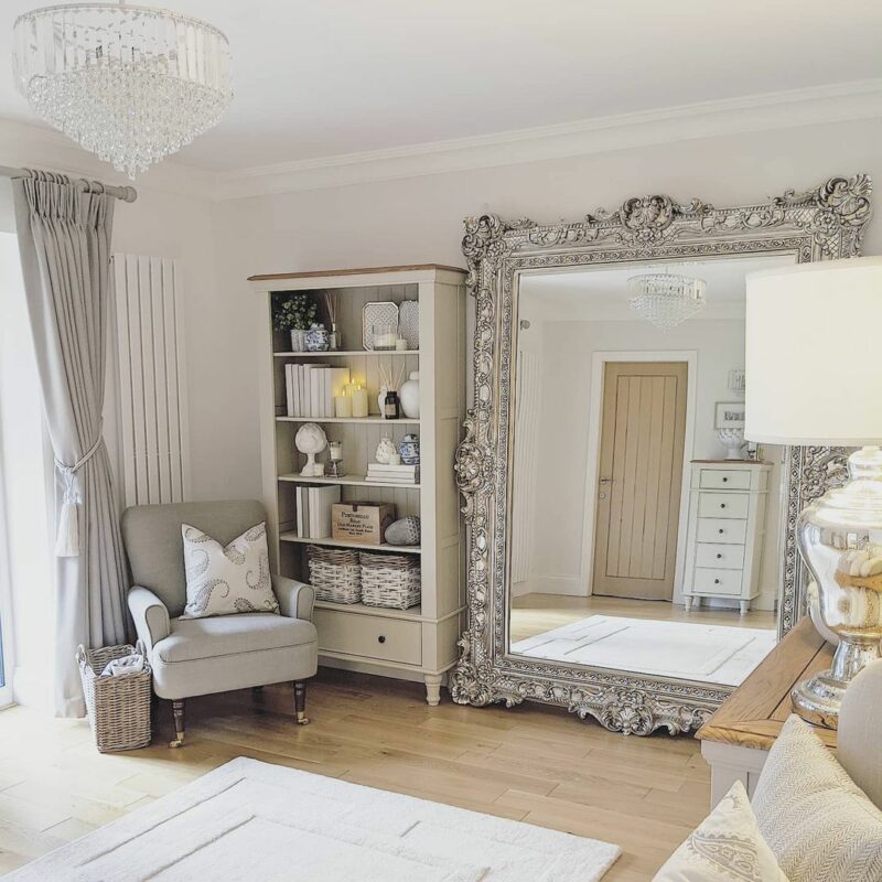 Oak Furnitureland cream painted Shay bookcase in luxe room with large silver statement wall mirror. 