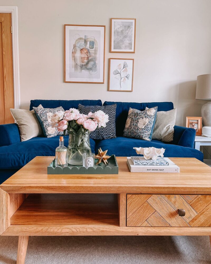 Parquet coffee table and dark blue velvet sofa in neutral living room scheme.