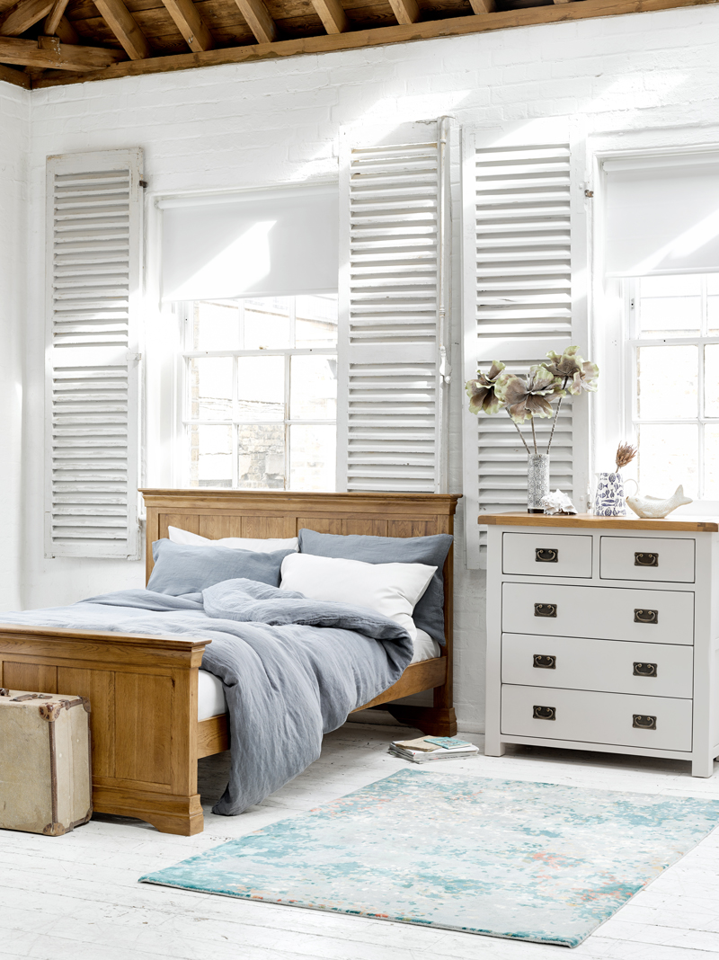 White painted chest of drawers with rustic wooden bed