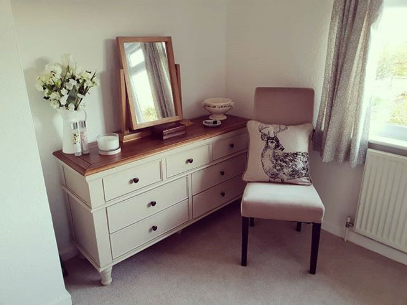 white painted chest of drawers in bedroom with fabric chair