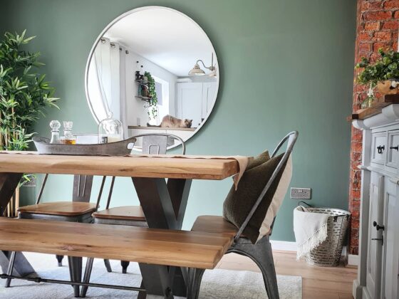 Oak and metal industrial-style Brooklyn dining table with green walls and plants.