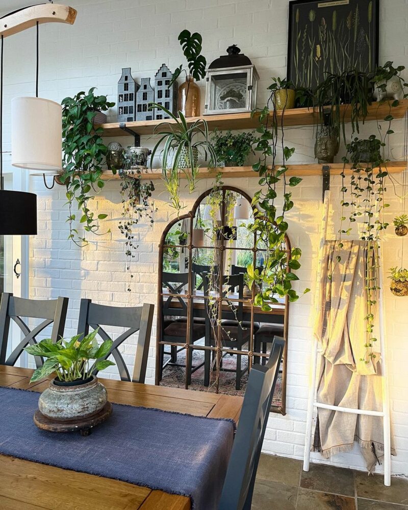 Oak Furnitureland Highgate dark blue dining table in a bright plant-filled space.