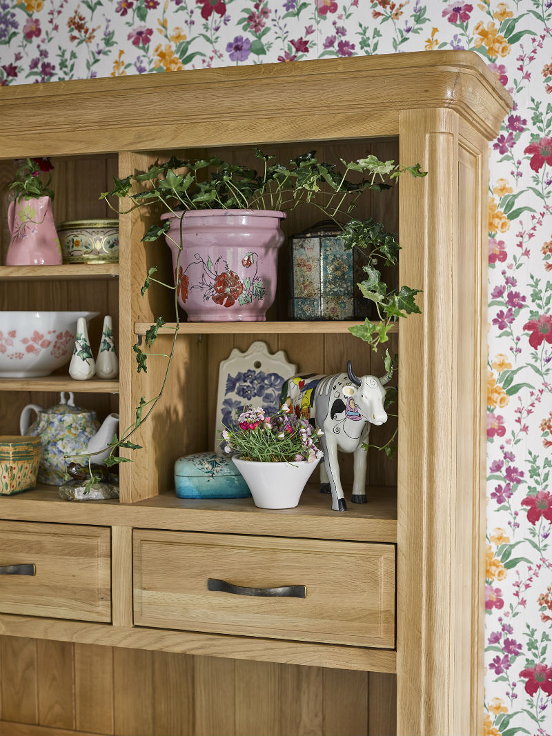 large oak dresser against floral patterned wallpaper