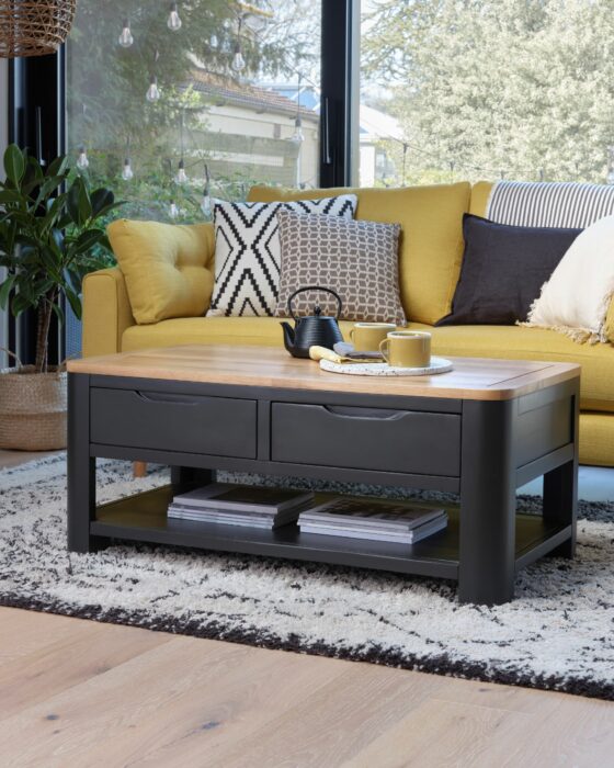Dark grey Grove coffee table in a living room with a yellow sofa and monochrome cushions.