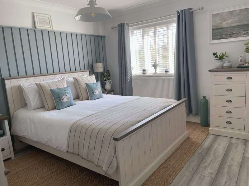 Oak Furnitureland white painted Brompton bed and tallboy in coastal-themed bedroom.