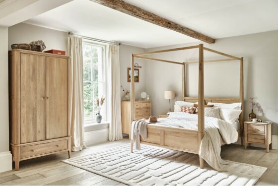 Elegant four-poster natural oak Newton bedroom in a neutral bedroom featuring the whole collection, including wardrobe and chest of drawers, with neutral accents.