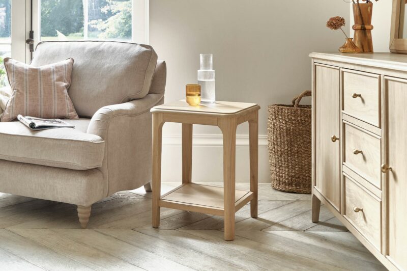 Close up of the Newton side table next to the Stanmore armchair in a neutral living space.