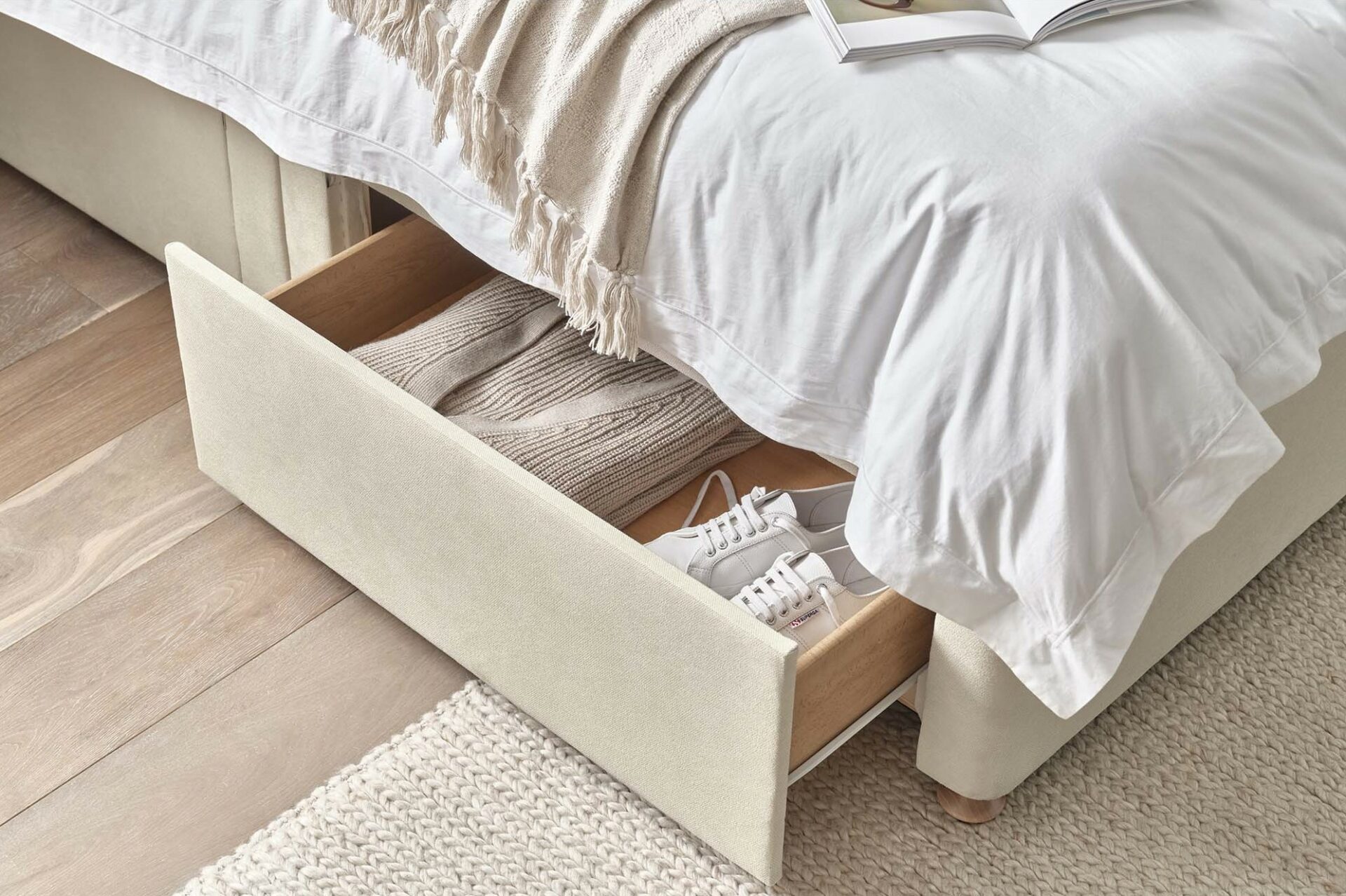 Oak Furnitureland Eden divan bed with drawer storage that's open to reveal clothes and shoes.