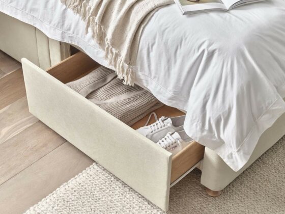 Oak Furnitureland Eden divan bed with drawer storage that's open to reveal clothes and shoes.