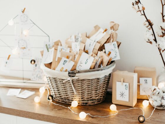 DIY advent calendar in a wicker basket on a table with fairy lights.