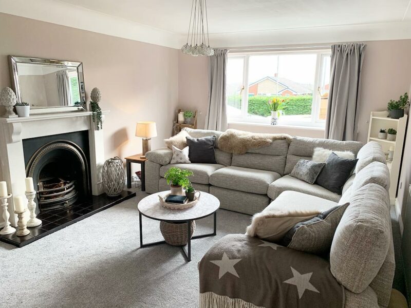 Large grey modular corner sofa in a new build living room with a fireplace and elegant accessories.
