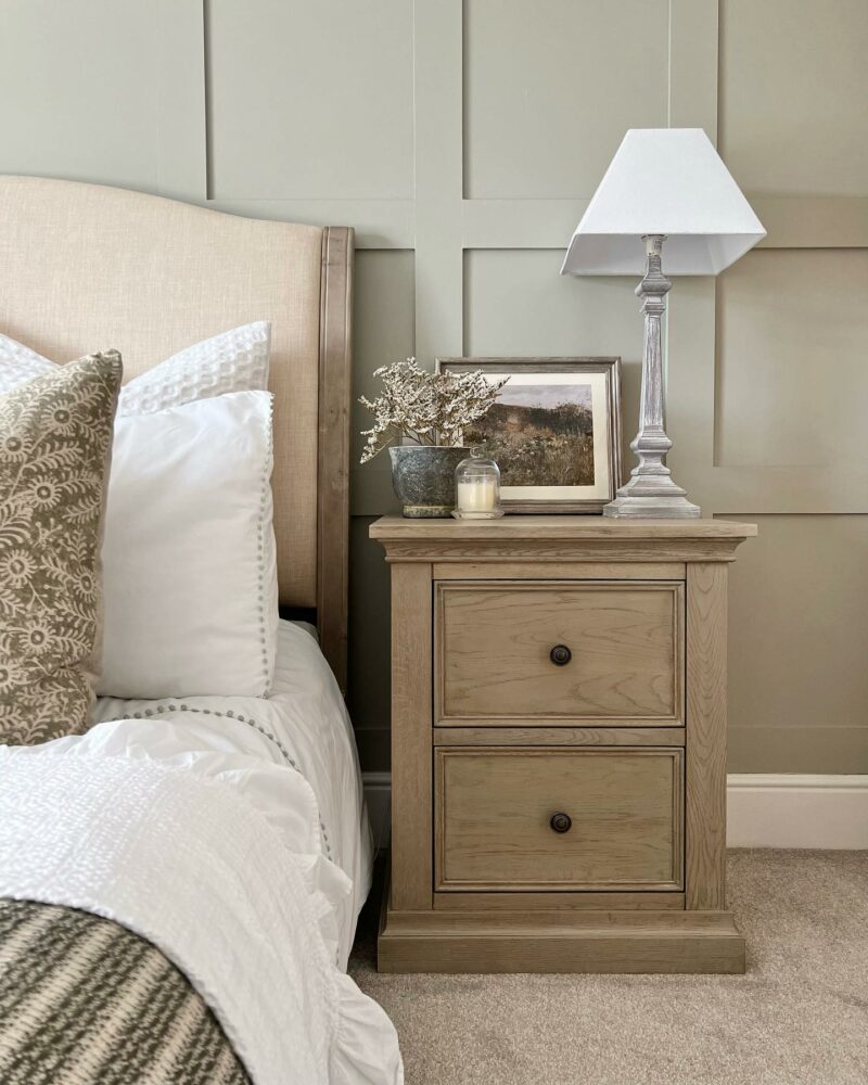 Oak Furnitureland Burleigh weathered oak bedside table in a muted bedroom with wall panels.
