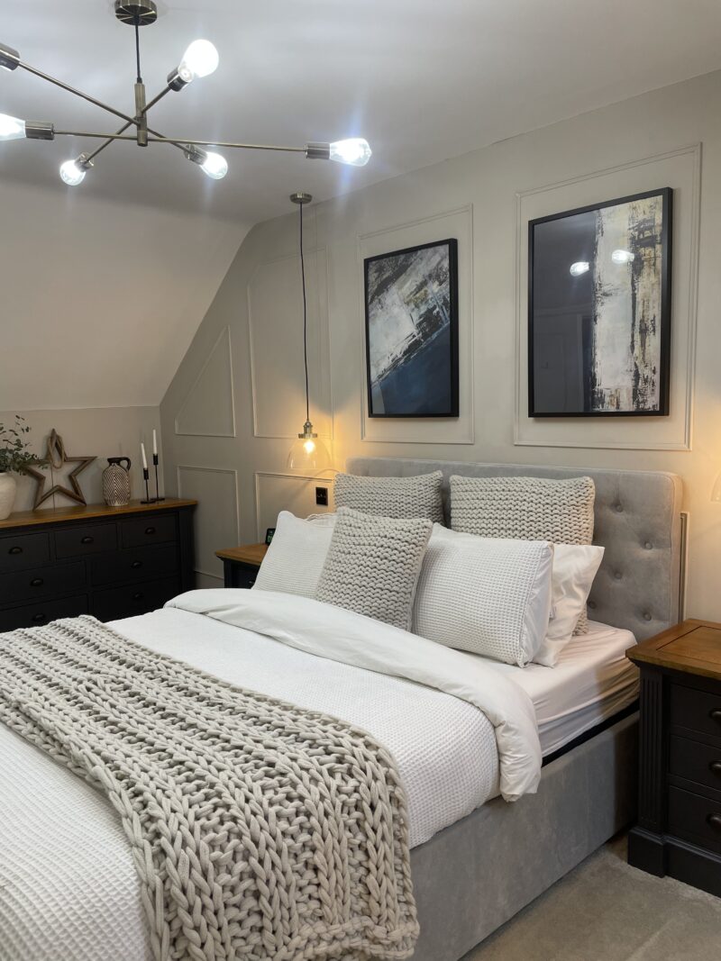 Grey upholstered bed in grey and blue bedroom with Oak Furnitureland Highgate furniture range.