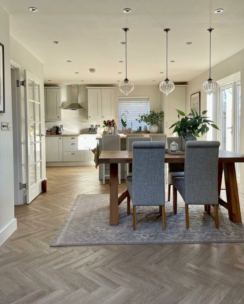 Open plan kitchen featuring grey scroll back fabric dining chairs.