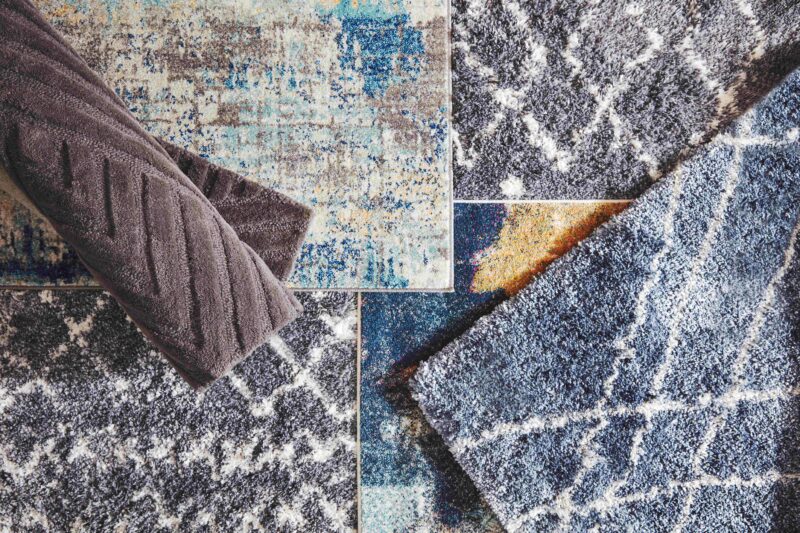 Flatlay of colourful shaggy rugs in blue, grey and brown tones.