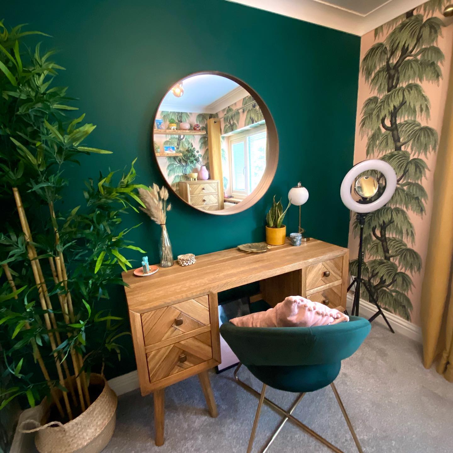 Parquet dressing table in a room with a bright green wall and botanical wallpaper.