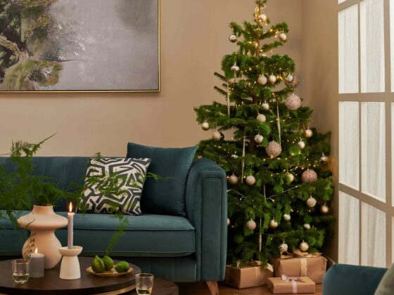 Living room featuring the Porter blue velvet sofa with a Christmas tree next to with elegant gold bauble, a set of nesting coffee table in a dark wood stain with gold legs.