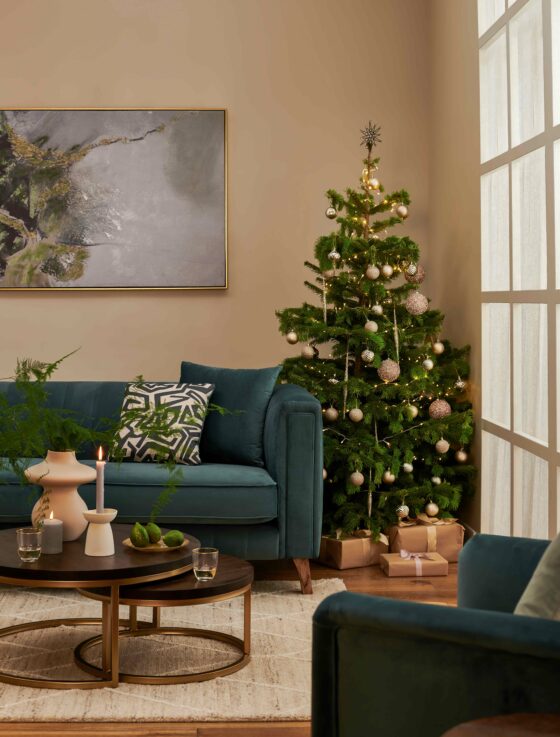 Living room featuring the Porter blue velvet sofa with a Christmas tree next to with elegant gold bauble, a set of nesting coffee table in a dark wood stain with gold legs.
