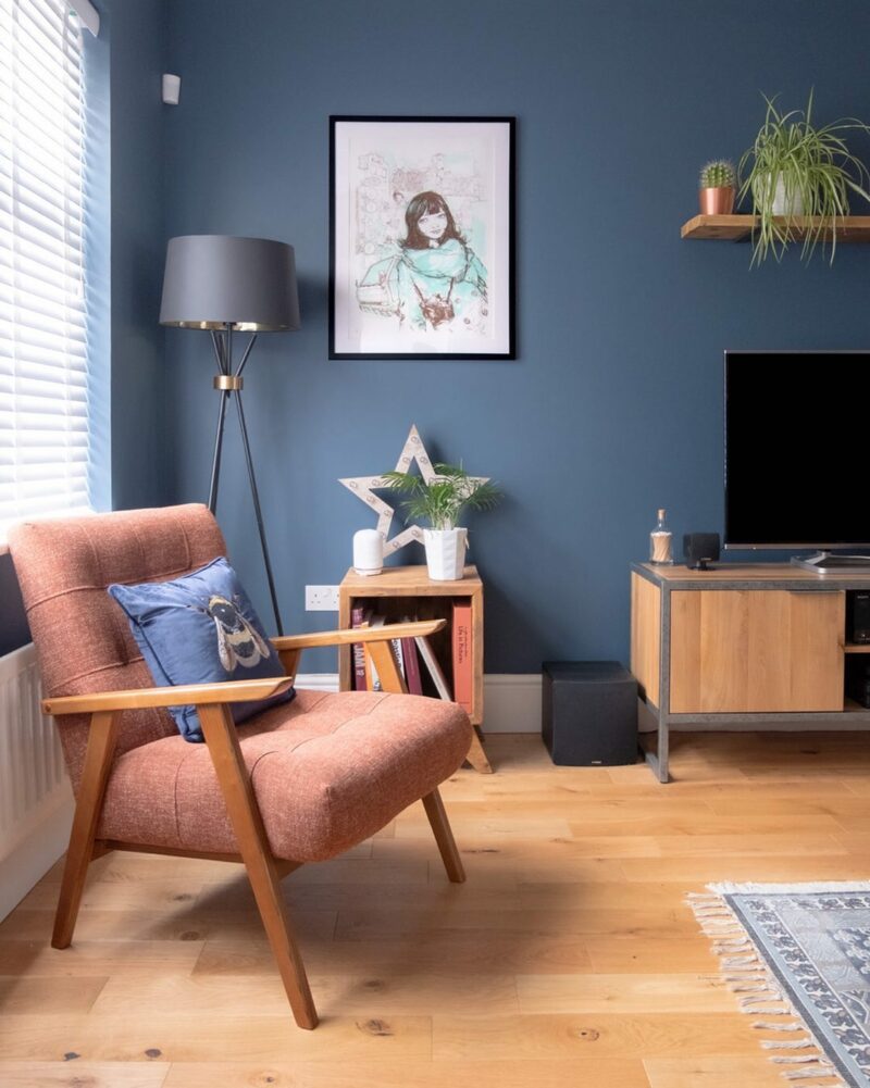 Painted blue living room featuring the Brooklyn oak and metal TV unit, a floor lamp and a terracotta armchair.