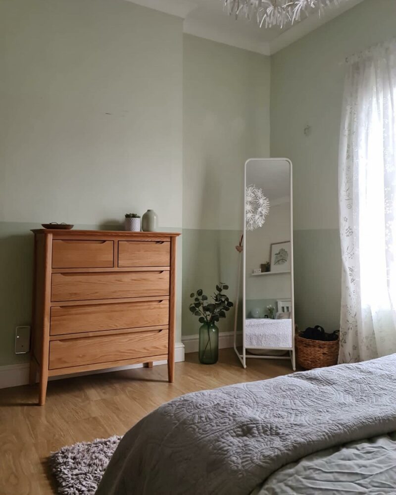 Scandi-style natural oak chest of drawers in a bedroom with a full length mirror.