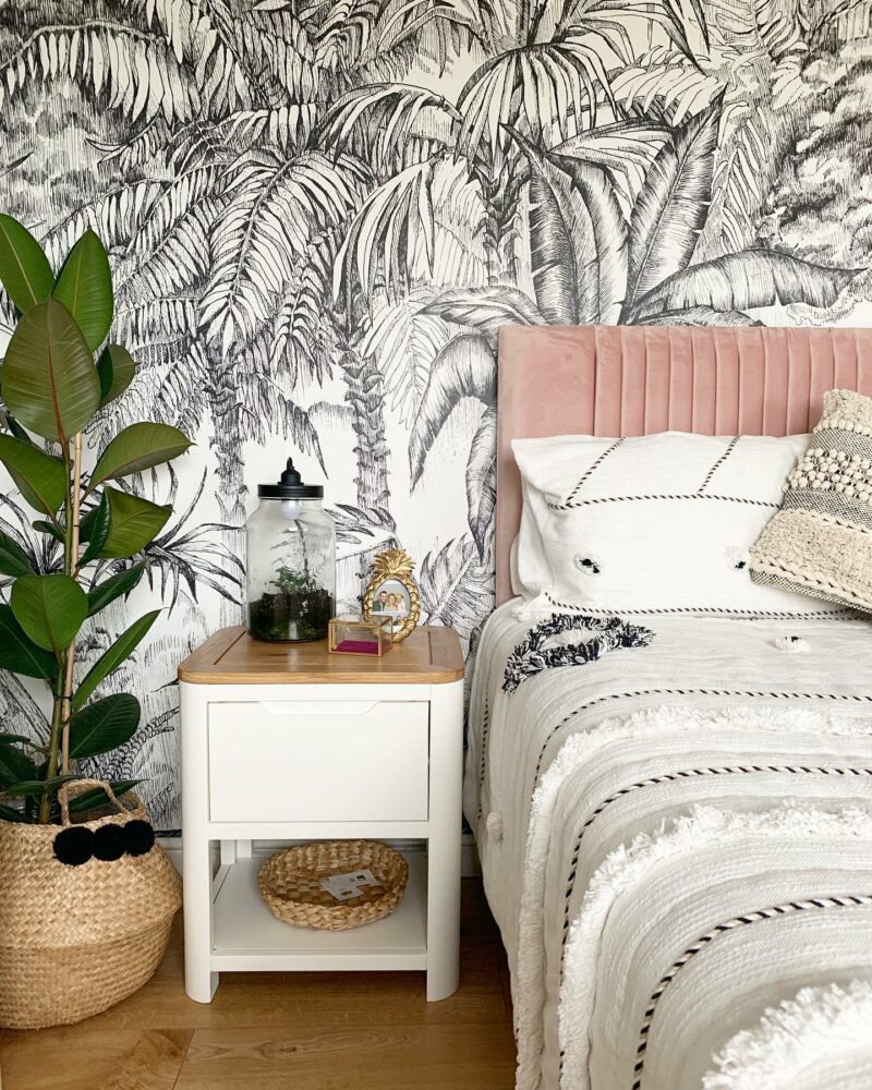 Oak Furnitureland Hove off-white painted bedside table with botanical walls & a pink velvet bed.