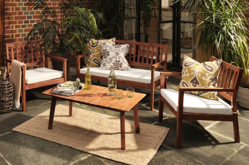 Oak Furnitureland Java 4-piece teak garden lounge set, with colourful pillows and an outdoor rug.