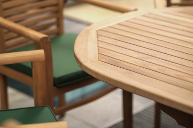 Close up of the Oak Furnitureland Cayman teak dining set and chairs with dark green cushions.