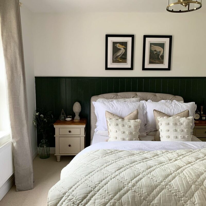 Oak Furnitureland Shay almond grey painted bedside tables in a bedroom with dark green panelling and cream bedding. 