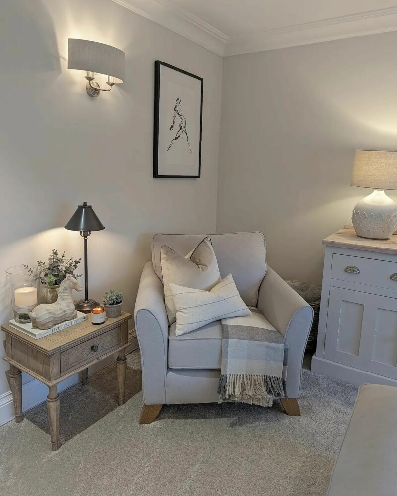 Oak Furnitureland Jasmine pale grey armchair, with tonal cushions and throw, in an elegant cream living room corner.
