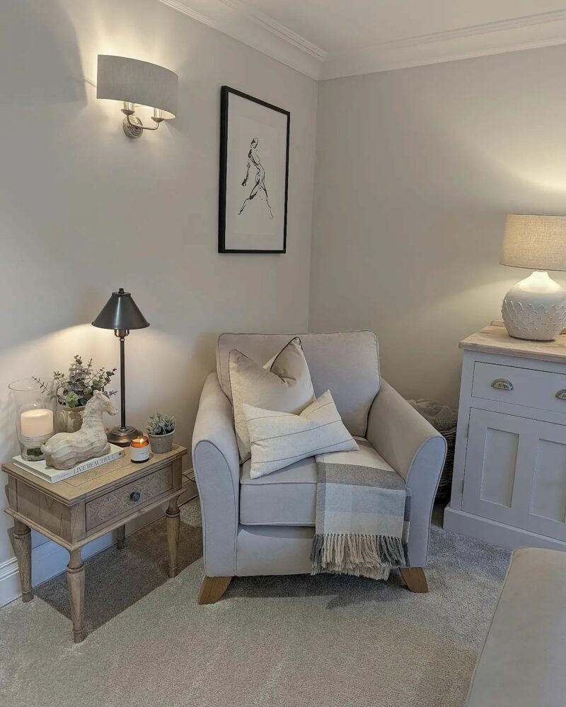 Oak Furnitureland Jasmine pale grey armchair, with tonal cushions and throw, in an elegant cream living room corner.