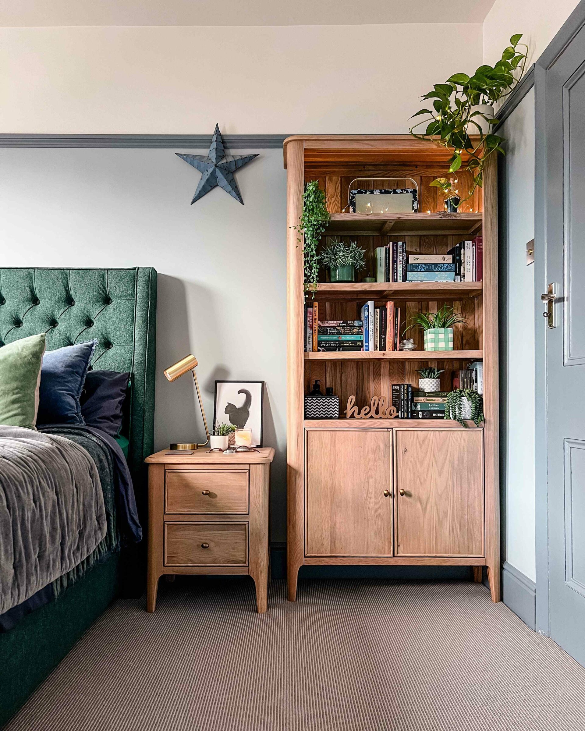 A bed, a bookcase and bedside table-bedroom furniture-upholstered double bed-wooden bedside table with drawers-wooden bookcase-green upholstered bed-grey wall colour
