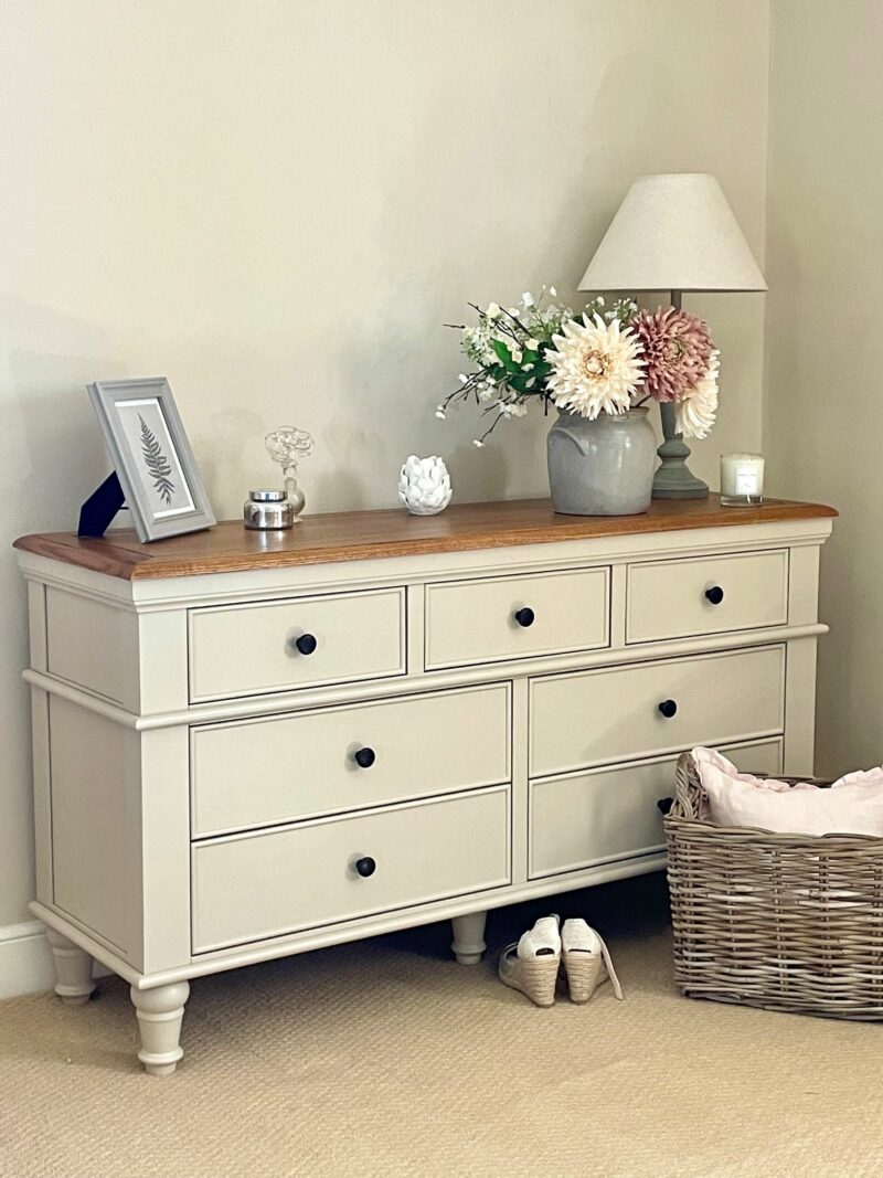 Almond grey and oak topped Shay 7-drawer chest in neutral scheme with flowers.