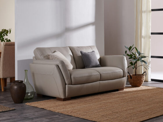 Neutral leather sofa in a living room with hessian rug and plants.